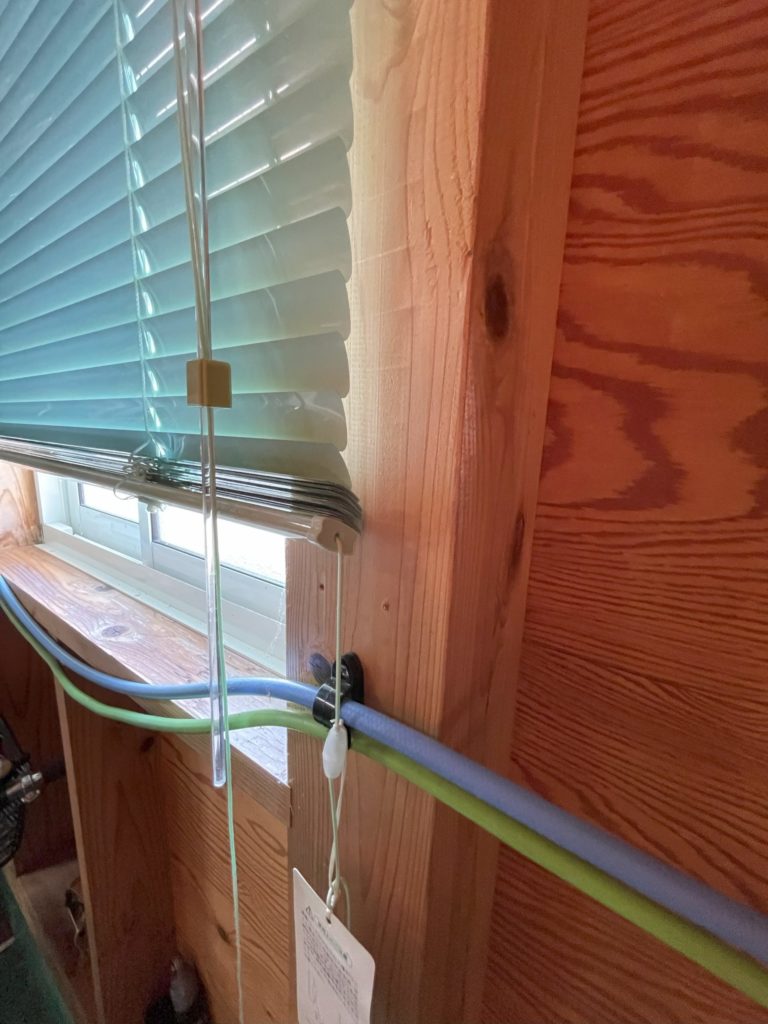 ガレージ壁際に沿わせた、エアーホース（水色）と電源コード（緑）の様子