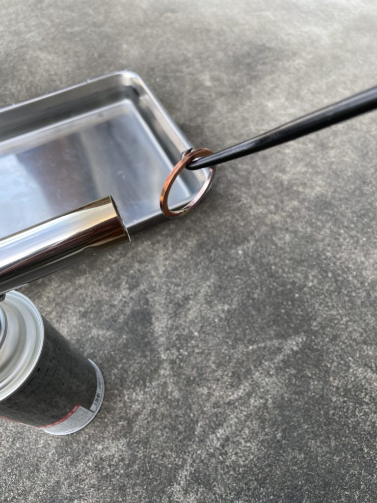 銅ワッシャーをスプリングフックに引っ掛けてトーチでで加熱している画像