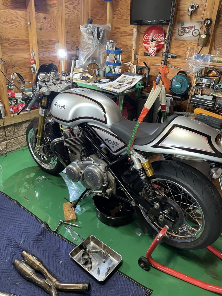 Norton Commando961のオイル抜き中のガレージ風景画像。メンテナンススタンドを使用した状態